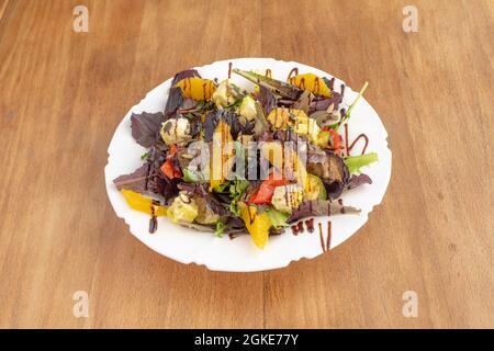 Salat aus gebratenem Gemüse, Sonnenblumenkernen, Feta-Käse und Orangenstücken mit Balsamico-Essig Stockfoto