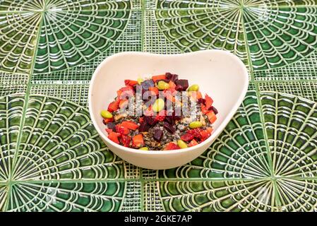 Linsensalat mit Paprika, Erdbeeren, grünen Bohnen und Rüben in einer weißen Schüssel auf einem auffälligen grünen Porzellantafel Stockfoto