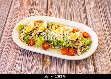 Toller und großzügiger gemischter Salat mit gehacktem gekochtem Ei, Nordbonito aus der Dose, halbierten Kirschtomaten und Eisbergsalat mit violetter Zwiebel Stockfoto