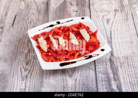 Salat aus gerösteten Piquillo-Paprika mit Thunfischkonserven auf einem Holztisch. Stockfoto