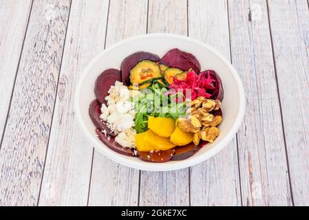 Rübensalat mit Gurken, roten Zwiebeln aus der Dose, Feta-Käse, Rucola, Orangenscheiben, Stücke von kalifornischen Walnüssen in einer Pappschale für die Lieferung nach Hause Stockfoto