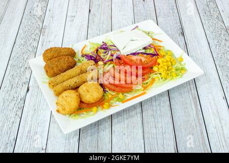 Gemüse-Kebab-Salat mit frischem Käse, Mais, Kroketten, Käsefinger und Nuggets auf weißem Teller Stockfoto