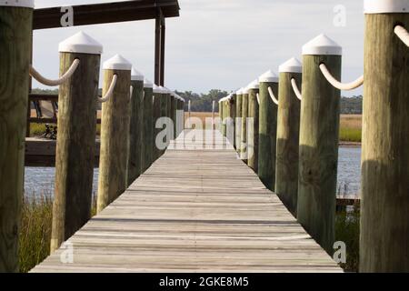 Holzdock mit Seilen an sonnigen Tagen mit Salzmarsch in der Ferne Stockfoto