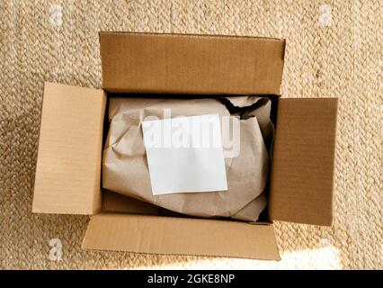 Ansicht der neuen Paketzustellung beim Auspacken auf dem Boden mit weißem Papier von oben Stockfoto