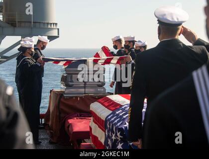 PAZIFISCHER OZEAN (29. März 2021) Seeleute falten das nationale Fähnchen während einer Beerdigung auf der Seezeremonie an Bord des amphibischen Sturmschiffs USS Essex der Wasp-Klasse (LHD 2). Essex führt derzeit Routineoperationen in der dritten US-Flotte durch. Stockfoto