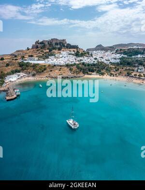 Segelboot auf türkisfarbenem Meer, Sandstrand, Akropolis von Lindos, alte Zitadelle auf einer steilen Klippe, Lindos, Rhodos, Dodekanes, Griechenland Stockfoto