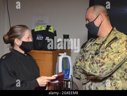 JACKSONVILLE, Florida (31. März 2021) - LT. Cmdr. Clifton Wilcox, Arbeitsmediziner und Notarzt für das Naval Hospital Jacksonville und die Navy Region Southeast, spricht mit dem Senior Chief Hospital Corpsman Tanda Blair am Standort des Krankenhauses für COVID-19-Impfstoffe. Wilcox, ein gebürtiger aus Joliet, Illinois, sagt: „Es ist von entscheidender Bedeutung, dass jeder den Impfstoff erhält, weil er dazu beitragen wird, unsere Rückkehr zum Normalzustand zu beschleunigen und weil je länger große Gruppen von Menschen ungeimpft bleiben, desto mehr mutiert das Virus weiter, da es immer mehr Menschen infiziert Stockfoto