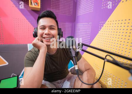 Ein glücklicher asiatischer Mann zeichnet in seinem Studio einen Podcast auf Stockfoto