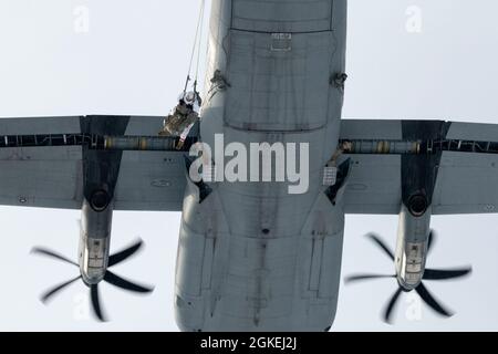 Die Jumpmaster der Armee des 4. Kampfteams der Infanterie-Brigade (Airborne), 25th Infantry Division, U.S. Army Alaska, beobachten, wie ein Fallschirmjäger von einem C-130J Super Hercules der US Air Force während eines simulierten Fallschirmsprungsangriffs über die Malemute Drop Zone auf der Joint Base Elmendorf-Richardson, Alaska, 31. März 2021, springt. Die Luftwaffe des 374. Luftlift-Flügels aus dem japanischen Yokota Air Base stellte Luftmittel für den Trainingsbetrieb zur Verfügung. Die Soldaten sind Teil der einzigen pazifischen Luftbrigade der Armee, die in der Lage ist, schnell weltweit zu stationieren, und werden für die Durchführung militärischer Operationen in aus geschult Stockfoto