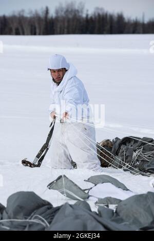 Armee-Spc. Wimer Angulo, ein Fallschirmjäger mit Delaware Company, 1. Bataillon, 501. Fallschirmjäger-Regiment, 4. Infanterie-Brigade-Kampfteam (Airborne), 25. Infanterie-Division, U.S. Army Alaska, erholt seine taktischen Fallschirmsysteme T-11 während eines simulierten Fallschirmangriffs in der Malemute Drop Zone auf der Joint Base Elmendorf-Richardson, Alaska, 31. März 2021. Die Soldaten sind Teil der einzigen pazifischen Luftbrigade der Armee, die in der Lage ist, sich schnell weltweit zu entsenden, und werden für militärische Operationen unter strengen Bedingungen geschult. Stockfoto