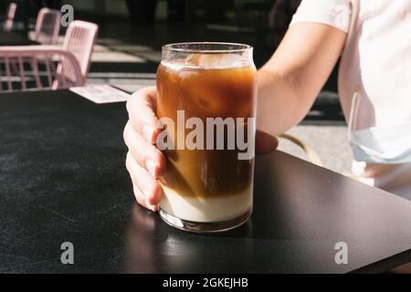 Frau hält ein leckeres Glas kalten Brühkaffees mit Milch in der Hand. Stockfoto