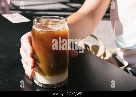 Frau hält ein leckeres Glas kalten Brühkaffees mit Milch in der Hand. Stockfoto