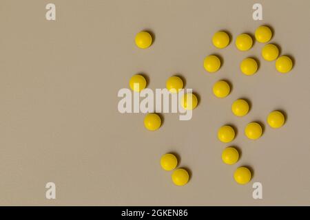 Gelbe Tabletten auf der Tischplatte verstreut Stockfoto