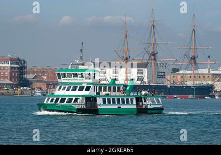 Portsmouth, England, Großbritannien. 2021. Die Gosport-Passagierfähre, die den Hafen von Portsmouth überquert und nach Gosport einfährt. HMS Warrior ein historisches Schiff im Hintergrund. Stockfoto