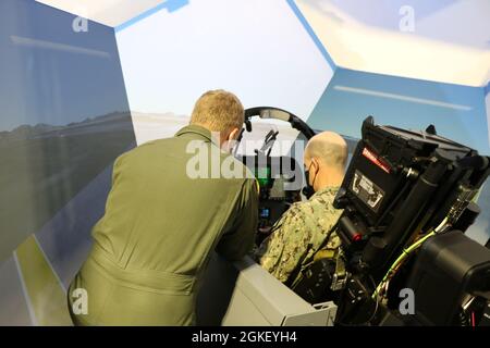 Lt. Bef. Kurt Garman, Carrier Air Wing (CVW) 5 Landing Signals Officer, links, führt eine Unterredungen zum Vice ADM durch. Bill Merz, Kommandant der 7. US-Flotte bei einem Besuch des Operational Training Complex (OTC) FA-18 Simulators im Rahmen einer Tour durch MCAS Iwakuni, Japan, April 2. Ziel des Besuchs war es, sich auf die Zusammenarbeit mit den nach vorne eingesetzten Marineeinheiten wie Carrier Air Wing (CVW) 5 zu konzentrieren, die die Operationen der Carrier Strike Group (CSG) 5 und der 7. US-Flotte unterstützen. Stockfoto