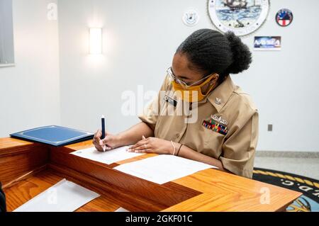 WASHINGTON, DC (2. April 2021) – der kulinarische Spezialist der 2. Klasse Sheniqua Lee unterzeichnet nach einer Zeremonie an Bord des Washington Navy Yard die Unterlagen zur Neuanstellung. Stockfoto