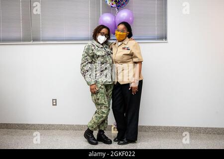 WASHINGTON, DC (2. April 2021) – kulinarische Spezialistin der 2. Klasse Sheniqua Lee, rechts, posiert mit den Gästen der Zeremonie, nachdem sie an Bord des Washington Navy Yard neu aufgenommen wurde. Stockfoto