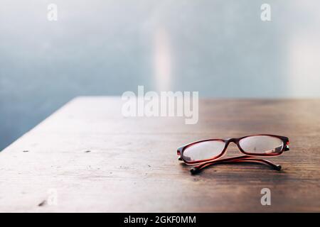 Verschwommenes Sehen - Lesebrille für ältere Menschen auf Holztisch Nahaufnahme Weichfokus Stockfoto