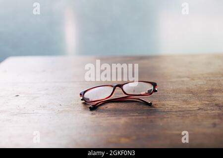 Schreibtisch für alte Schriftsteller - Lesebrille für ältere Menschen auf einem Holztisch mit Nahaufnahme-Weichfokus Stockfoto