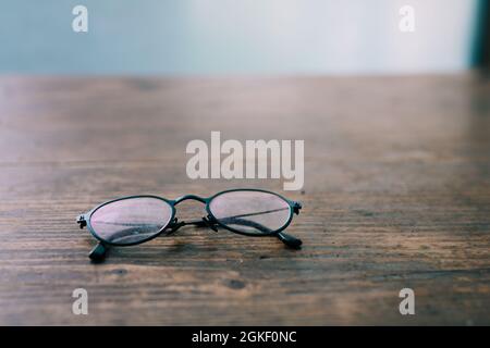 Schlechte Augen oder Kurzsichtigkeit - Lesebrille für ältere Menschen auf Holztisch Nahaufnahme Weichfokus Stockfoto