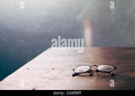 Robuster Arbeitstisch aus Holz - Lesebrille für ältere Menschen auf Holztisch Nahaufnahme Softfokus Stockfoto