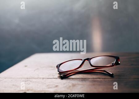 Lesebrille bei Sonnenlicht – für ältere oder weitsichtige Personen, Holztisch Nahaufnahme Weichfokus Stockfoto