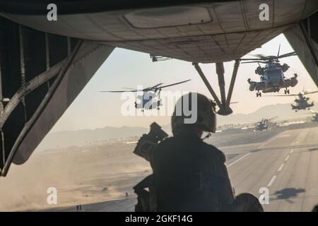 US Marine Corps Staff Sgt. Cory Emily, eine Cheflehrerin der CH-53E Super Hengst Crew, mit Marine Aviation Weapons and Tactics Squadron One (MAWTS-1), untersucht die Fluglinie während des Starts, an Bord eines CH-53E Super Hengst, zur Unterstützung des Weapons and Tactics Instructor (WTI) Kurses 2-21, auf der Marine Corps Air Station Yuma, in Yuma, Arizona, 3. April, 2021. WTI ist eine siebenwöchige Schulungsveranstaltung, die von MAWTS-1 veranstaltet wird und standardisierte fortgeschrittene taktische Schulungen und Zertifizierungen von Instruktorenqualifikationen bietet, um die Ausbildung und Bereitschaft der Meeresluftfahrt zu unterstützen, und hilft bei der Entwicklung und Beschäftigung Stockfoto