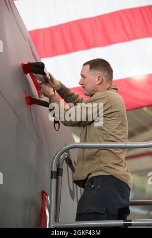 US Air Force Tech. Sgt. Tony Scolaro, ein Flugzeugbetreuer am 167. Luftlift-Flügel in Martinsburg, West Virginia, legt während einer Korrosionsschutzwäsche am 5. April 2021 Sperrpapier auf Teile eines C-17 Globemaster III-Flugzeugs. Das Sperrpapier wurde auf große Teile des Flugzeugs aufgetragen, um empfindliche Bereiche vor Wasser und Reinigungsmitteln zu schützen. Stockfoto