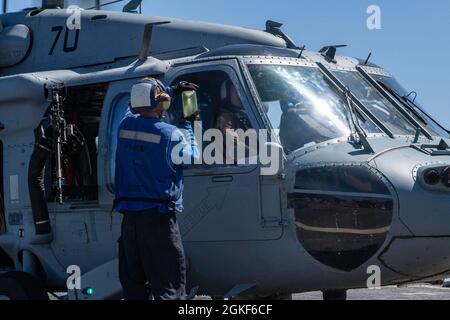 ARABIAN GULF (6. April 2021) – Gas Turbine Systems Technician (Mechanical) 3rd Class Jason Bird, beauftragt mit dem Lenkflugkörper-Zerstörer USS Laboon (DDG 58), zeigt den Piloten eines MH-60S Sea Hawk Hubschraubers, der an die „Chargers“ des Helicopter Sea Combat Squadron 26 angeschlossen ist, Kraftstoffproben Während des Flugbetriebs im Arabischen Golf, April 6. Laboon unterstützt die Charles de Gaulle Carrier Strike Group, während sie in das 5. Flottengebiet der USA eingesetzt wird und Marinestützungen durchführt, um die maritime Stabilität und Sicherheit in der Zentralregion zu gewährleisten und das Mittelmeer und den Pazifik über die zu verbinden Stockfoto