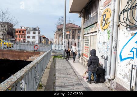 Taksim, Istanbul, Türkei - 03.12.2021: Türkische Bettler und ein Kind stehen und schauen Menschen vorbei an einer Straße mit Kopierraum Stockfoto