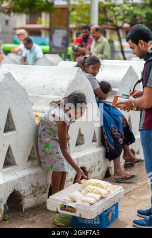 Ein kleines Mädchen verkauft Snacks auf einer Stadtstraße. Colombo, Sri lanka - 02.04.2018 Stockfoto