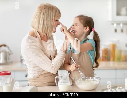 Reife Frau und Mädchen kochen mit Mehl berühren Nasen spielen Stockfoto