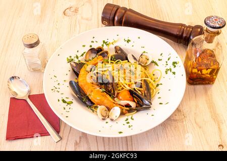 Italienische Spaghetti a la Marinera Rezept mit Garnelen, Muscheln, galizischen Muscheln und Tintenfisch mit würzigem Öl, Salz, Löffel und Pfeffer Shaker Stockfoto