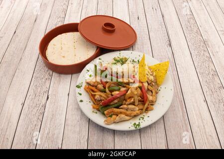 Präsentation von Chicken Fajitas mit sautiertem Gemüse, Tortilla-Chips, weißem Reis und Behälter für Weizentortillas auf hellem Hintergrund Stockfoto