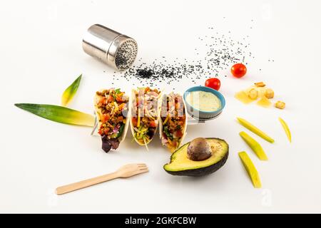 Chili con carne fajitas, Avocado, Mohn, Holzbesteck, Käse und Croutons auf weißem Tisch Stockfoto
