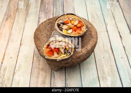 Burrito von Huhn fajitas mit Reis auf vulkanischem Stein molcajete typisch für Mexiko und dies auf Holztisch Stockfoto