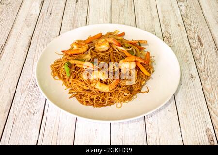 Gebratene Reisnudeln mit geschälten Garnelen und Gemüse in einem Wok mit Rezept aus einem asiatischen Restaurant Stockfoto