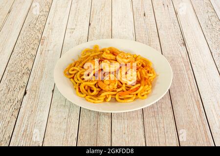 Gebratene udon-Nudeln mit geschälten Garnelen und Wok-sautiertem Gemüse auf weißem Teller Stockfoto