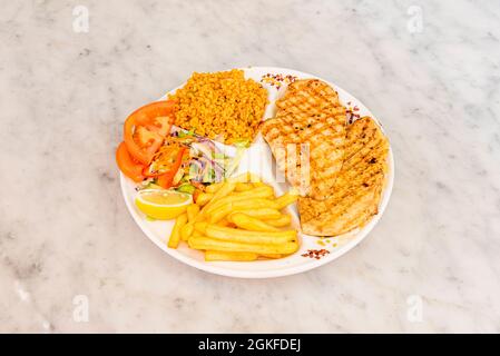 Menüteller in einem türkischen Restaurant mit Hühnerfilet und Beilagen aus Pommes, Salat und Bulgur Stockfoto