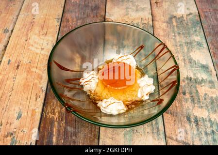 Köstliche hausgemachte Eiercreme mit Creme und Karamell in einer Glasschüssel auf Holzboden Stockfoto