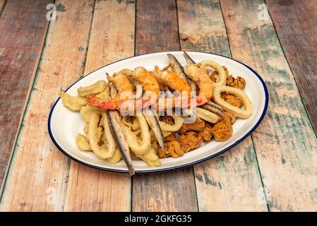Tolle andalusische Fisch- und Meeresfrüchte-Braten. Geschälte rote Garnelen in Tempura, gebratene Sardellen, marinierte Fischsoße, zerschlagene Tintenfischringe auf einem weißen Tablett Stockfoto