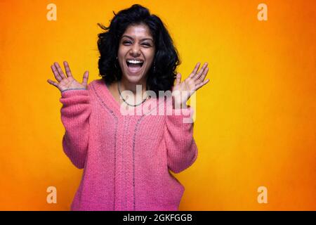 Schöne Sri Lanka Mädchen Posen stehen mit gelben hellen Hintergrund- Junge Frau lächelt verrückt lachen Stockfoto