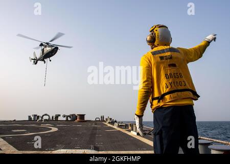 ARABISCHER GOLF (9. April 2021) – Boatswains Mate 2nd Class Joseph Coleman sendet Signale an einen Airbus SA 365 F Dauphin-Hubschrauber, der an den französischen Flugzeugträger FS Charles de Gaulle (R 91) befestigt ist, vom Flugdeck des Lenkrakenzerstörers USS Laboon (DDG 58) Während des Flugbetriebs im Arabischen Golf, April 9. Laboon ist Teil der Charles de Gaulle Carrier Strike Group, während er im Einsatzgebiet der 5. Flotte der USA eingesetzt wird, um die operationstechnische Lösung zu unterstützen und die maritime Stabilität und Sicherheit in der Zentralregion zu gewährleisten, indem er das Mittelmeer und den Pazifik über das We verbindet Stockfoto