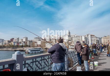 Eminonu, Istanbul, Türkei - 04.13.2021: Viele Türken mit Schutzmasken fischen auf der Galata-Brücke und halten Angelrute und warten darauf Stockfoto