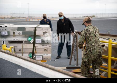 Aviation Ordnanceman 3rd Class Juan Torres, rechts, aus Milwaukee, der Waffenabteilung der USS Gerald R. Ford (CVN 78) zugewiesen wurde, transportiert während einer Munitionsaufladung auf dem Flugdeck am 9. April 2021 die Munitionsaufzüge auf einen der fortschrittlichen Waffensysteme des Schiffes. Ford befindet sich im Hafen von Norfolk, um im Rahmen ihrer 18-monatigen Test- und Testphase nach der Auslieferung eine geplante Wartungsmöglichkeit zu erhalten. Stockfoto