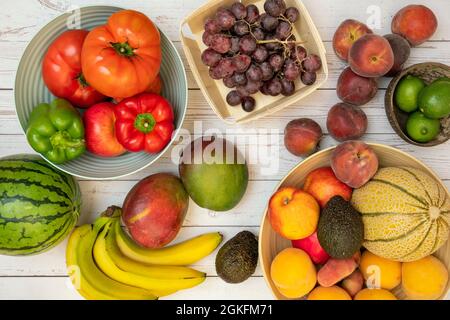 Bild von Obst und Gemüse in Obstschalen oder auf dem Tisch. Reife Bananen, Melonen und Wassermelonen, rote Trauben, Nektarinen und Limetten, Tomaten und pe Stockfoto