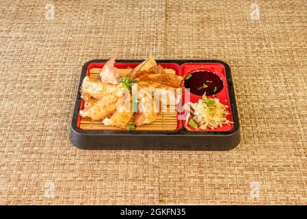 Japanische Speisekarte mit gegrillten Gyoza-Knödeln, Sojasauce und Beilagen auf Weidennieten Stockfoto