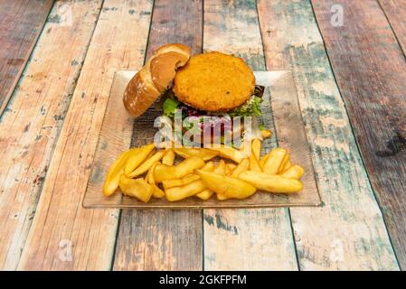 Hähnchenburger im Teig, mit viel Salat, rustikalem Brot und einer Seite Pommes Frites Stockfoto