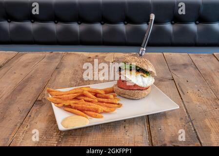 Hamburger mit Ei und Ziegenkäse, begleitet von gebratener Süßkartoffel Stockfoto