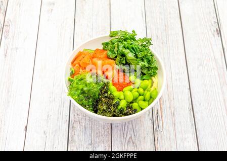 Norwegische Lachsschüssel mit Fischrogen, Wakame-Algen, gehacktem Grünkohl, Edamame-Bohnen und gehackten Zucchini. Stockfoto